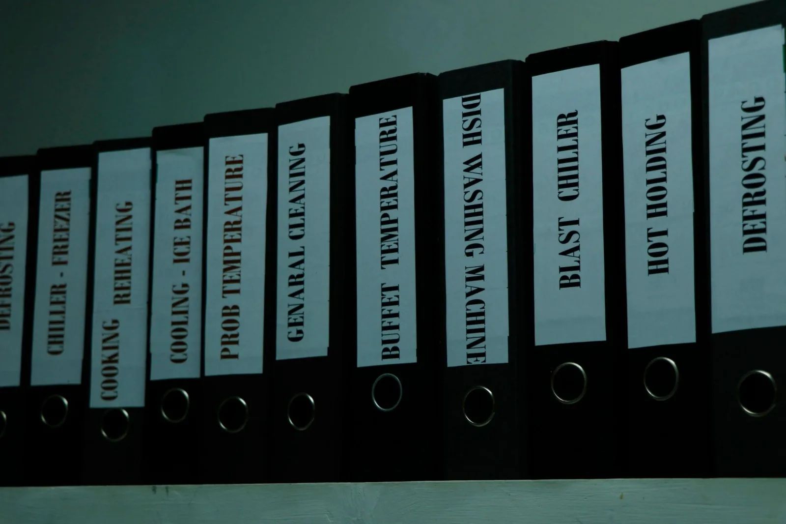 Shelf of food safety monitoring record binders organised by control point