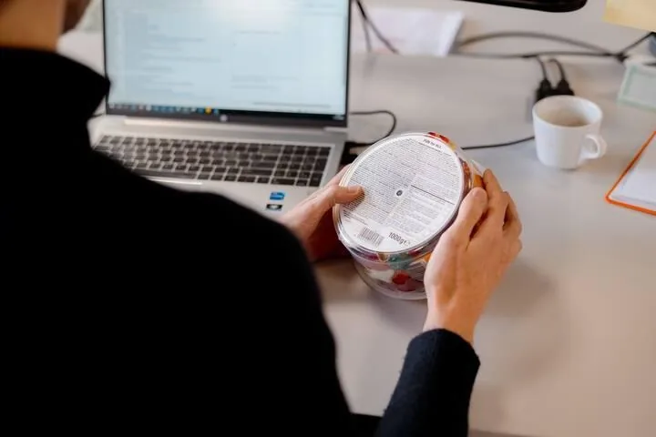Cross-checking a product label against renewal requirements on a laptop
